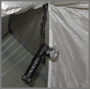 The Fenix MC11 dangling from ceiling clip on tent